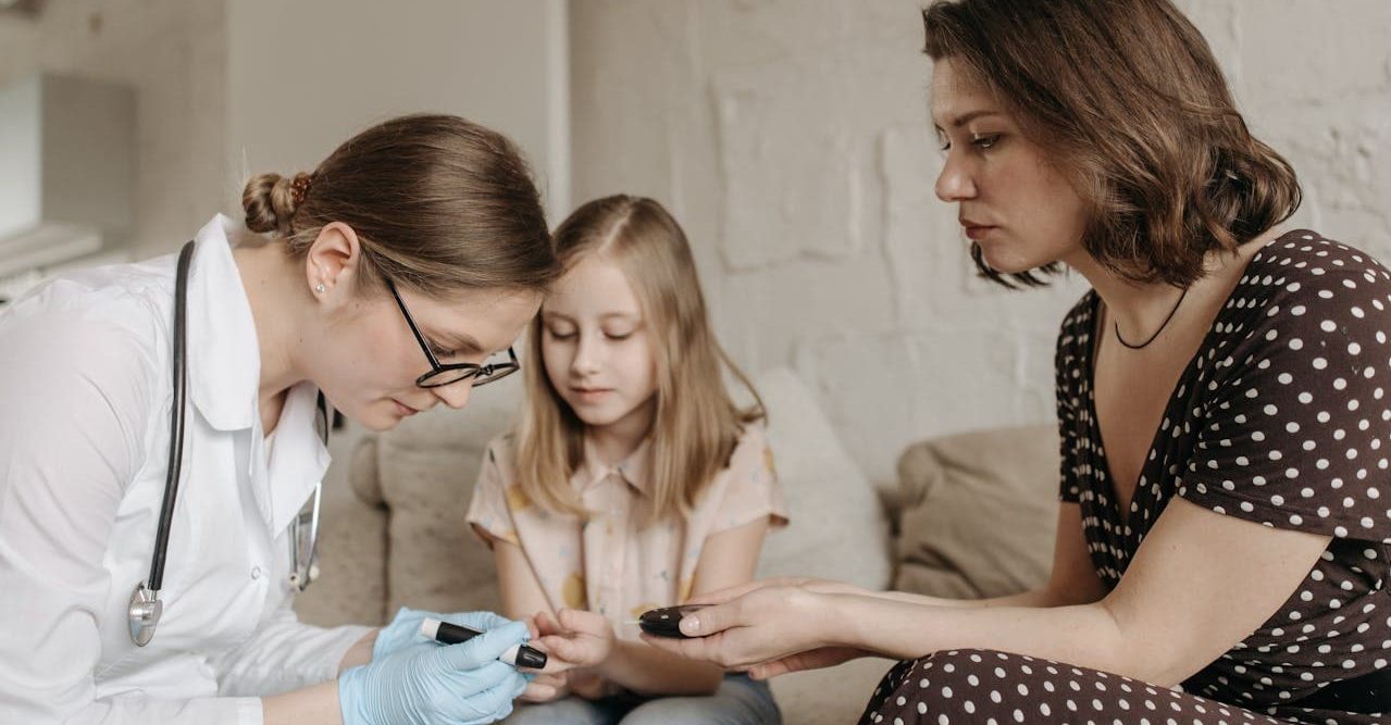 一名醫師與一名女子正在測量一個女孩的血糖。