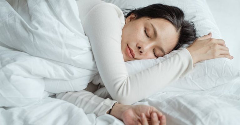 白色床單上熟睡的女性,展現舒適的睡眠環境。