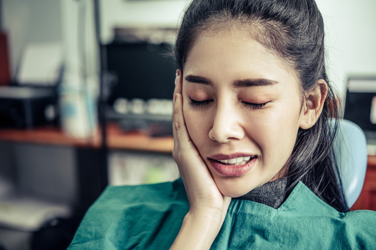 一位女子在牙科診所捂著臉頰。