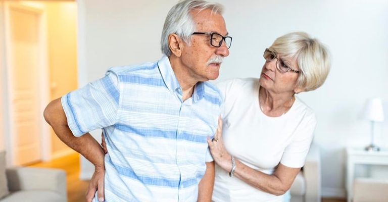 一位長者腰痛，另一位長者在家中攙扶他，突顯了骨密度症對老年人的影響。