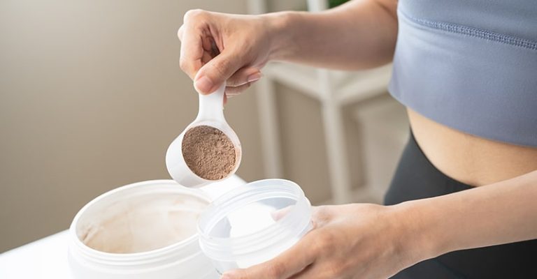 一名女子正在倒入乳清蛋白粉到搖搖杯中，準備補充運動後所需的蛋白質。