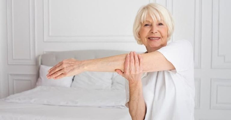 一名年長女子站在寢室中伸展手臂,展現骨骼健康的重要性。補充鈣質有助於維持靈活性與健康骨骼。