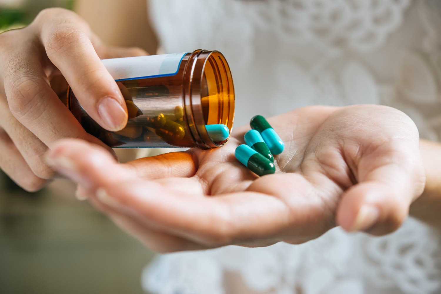 一隻手正從藥瓶中倒出膠囊藥丸,顯示甲鈷胺維生素 B12 保健品,有助於提高能量和健康。