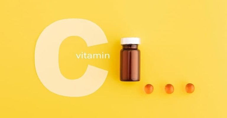 維他命 C 膠囊瓶子與幾顆維他命 C 保健品放在明亮的黃色背景上，強調維他命 C 補充對健康的重要性。
