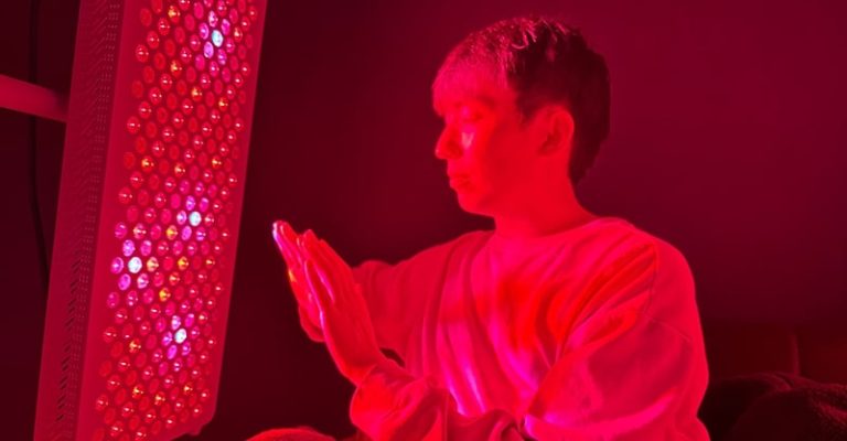 一名男子正在使用紅光儀來溫暖他的雙手。