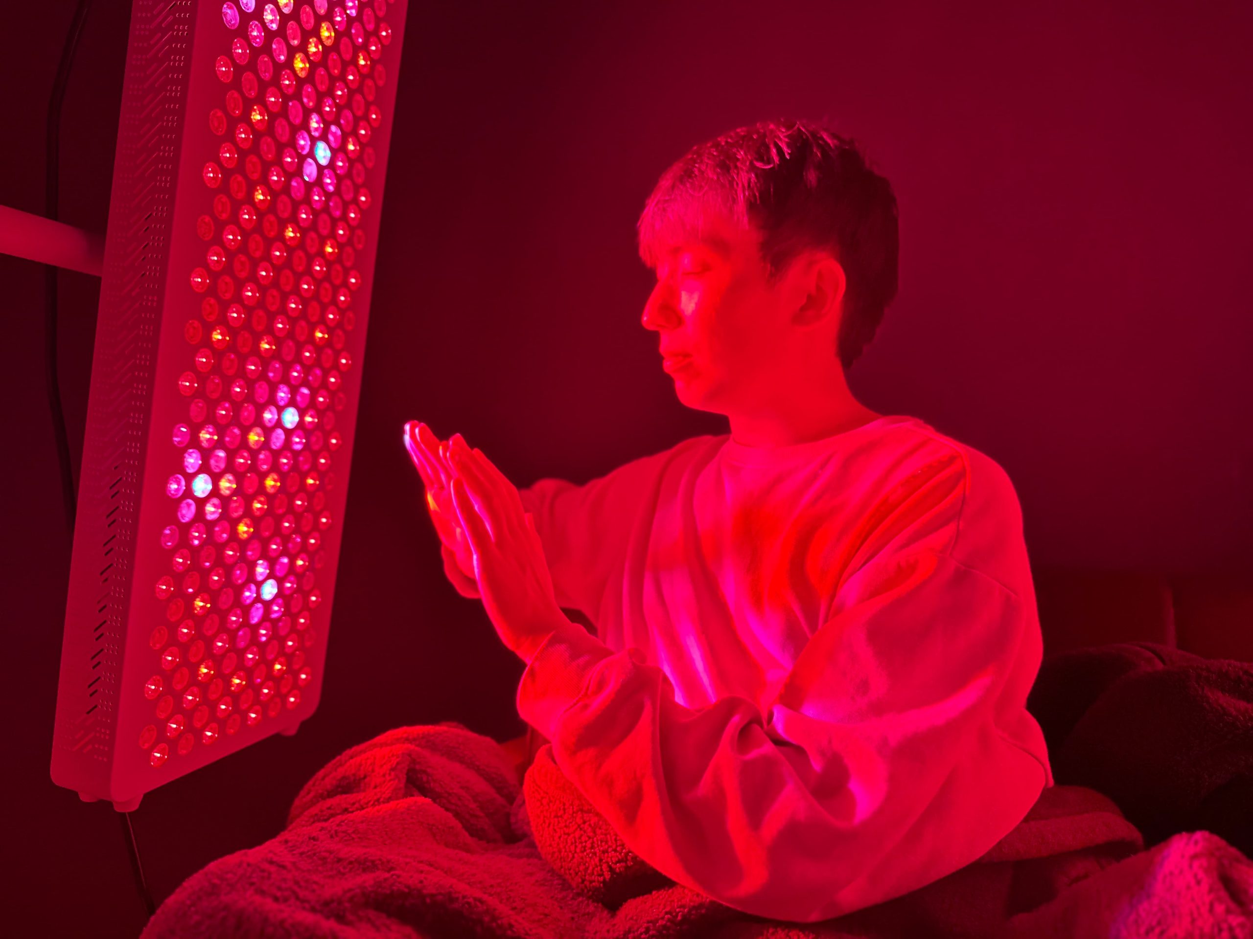 一名男子正在使用紅光儀來溫暖他的雙手。