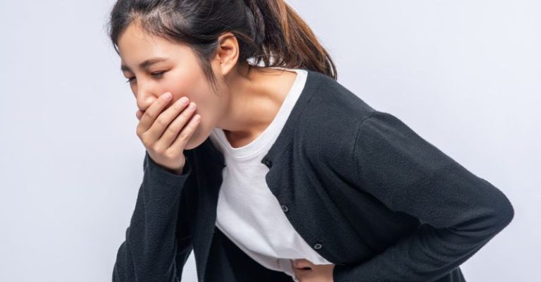 一名女子表現出胃痛和噁心的症狀，可能是由於胃食道逆流或消化不良，一手摀嘴、一手扶著肚子感到不適。