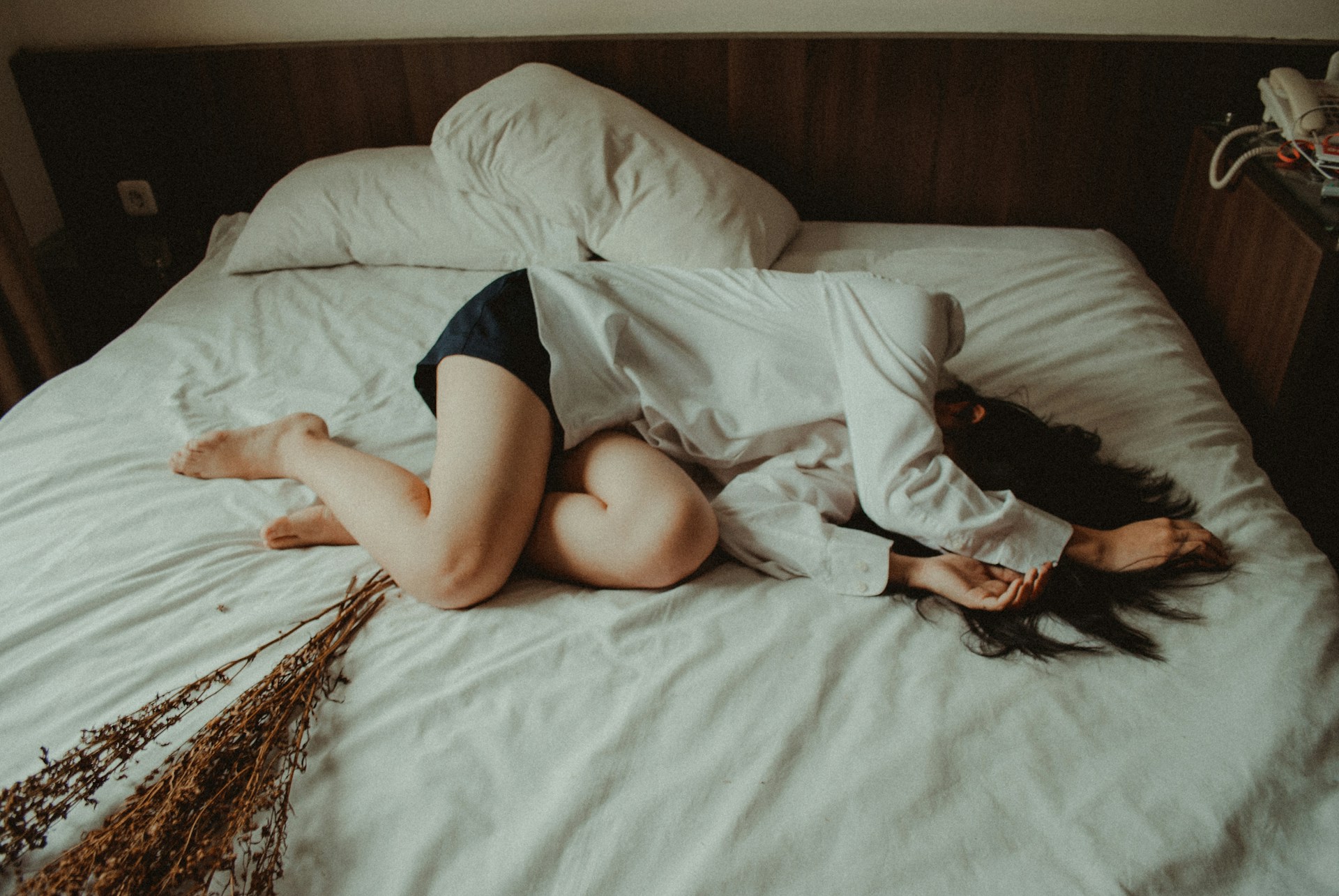一名女子因為經痛躺在床上休息,身體微微蜷縮,看起來很不舒服。