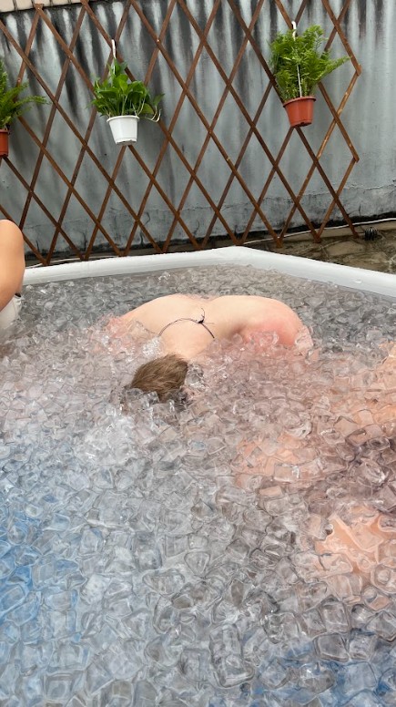 穿泳衣的人將全身泡進冰浴中,水池裡滿是冰塊。